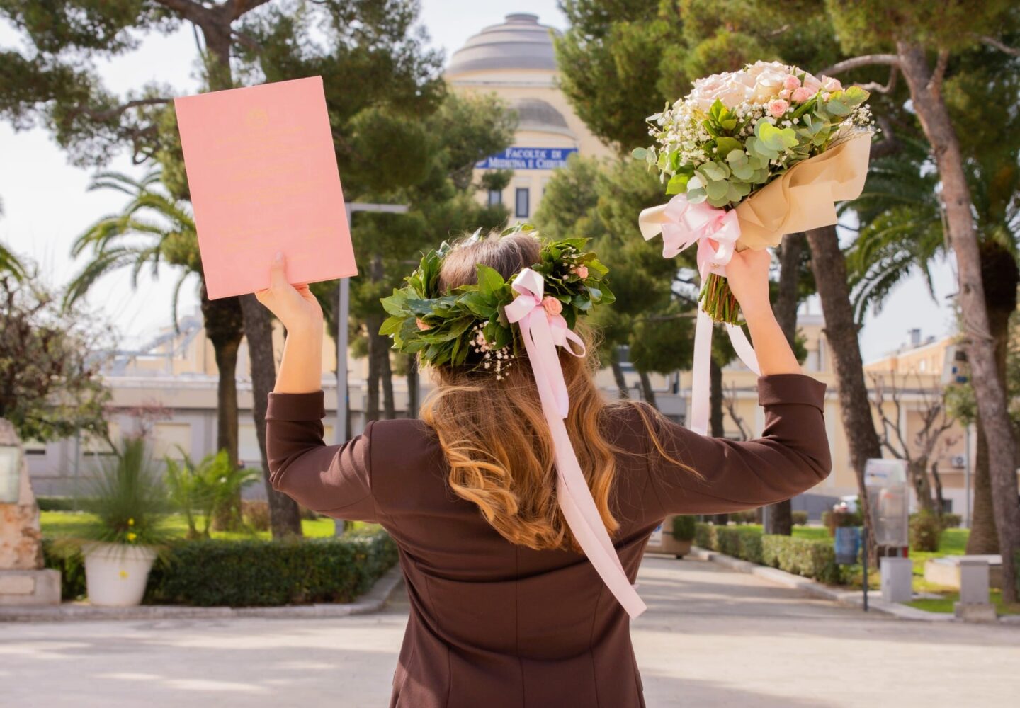 Dettaglio posteriore corona d'alloro fresca a Corato con nastri rosa e fiori, realizzata a mano per una laurea.